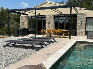 eine Terrasse mit einem Tisch, Stühlen und einem Pool in der Unterkunft villa avec piscine loft cabane in Nîmes