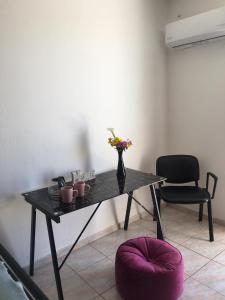 un tavolo con un vaso di fiori e una sedia di Layla' s Petite Home a Città di Kos