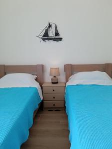 a bedroom with two beds with blue and white sheets at Angelouda's House in Karistos +19 photos