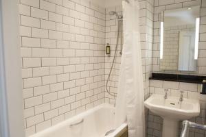a white tiled bathroom with a sink and a bath tub at Royal Ship in Dolgellau