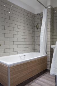 a bathroom with a bath tub with a shower at Royal Ship in Dolgellau
