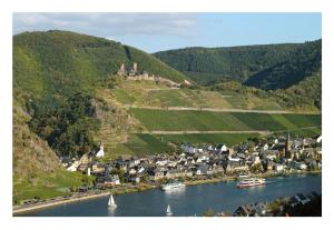 a river with boats in a town with a castle on a hill at Alkener Elfenhaus mit kostenlosen Gäste Ticket in Alken