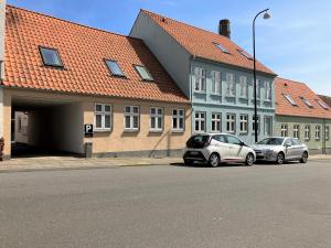 two cars parked in a parking lot next to buildings at Three-Bedroom Apartment In Fredericia in Fredericia
