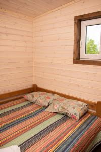 a bed in a small room with a window at Brīvdienu māja Rozes in Šķēde