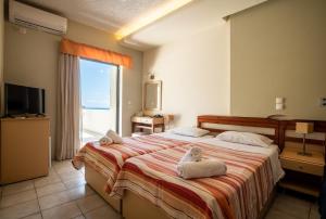 a bedroom with a large bed with towels on it at Polyrizos Hotel in Rodakino