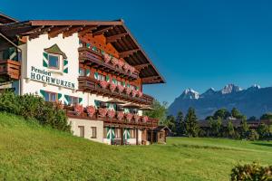 a hotel with flowers on the balconies on a hill at Hotel Garni Hochwurzen in Schladming