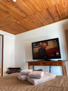 坎普斯杜若爾當的住宿－Recanto das Cerejeiras，电视坐在墙上,床上有毛巾