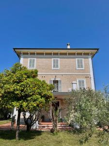duży ceglany dom z drzewem przed nim w obiekcie Villa Francesca Luxury w mieście Grottammare