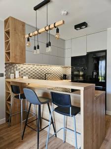 a kitchen with a large wooden island with bar stools at Nadmorski apartament premium in Gdynia
