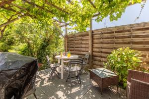 eine Terrasse mit einem Tisch, Stühlen und einem Zaun in der Unterkunft Rue Bien Assis avec jardin terrasse in Clermont-Ferrand