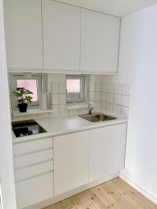 eine weiße Küche mit weißen Schränken und einer Spüle in der Unterkunft Great Modern Studio in Aalborg