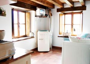 a kitchen with a white refrigerator and windows at Casa del Conde 2 - Ajanedo in Ajanedo