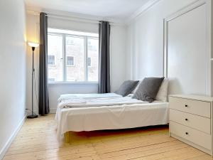 a white bedroom with a bed and a window at Nice Apartment Located Near Vesterbro in Aalborg