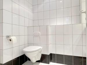 a white tiled bathroom with a toilet in it at Nice Apartment Located Near Vesterbro in Aalborg