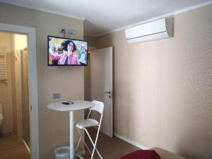 AFFITTACAMERE PIAZZA UNITA' في مونفالكوني: غرفة مع طاولة وتلفزيون على الحائط