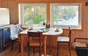 ein Esszimmer mit einem Tisch und 2 Fenstern in der Unterkunft Lovely Home In Flateby With Kitchen in Flateby