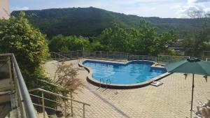 a swimming pool with an umbrella and mountains in the background at Kavarna Hills in Kavarna