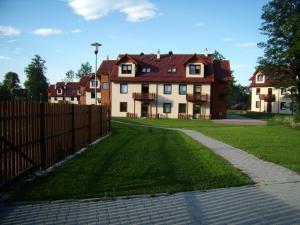 a large house with a fence and a grass yard at Apartament nad Łomniczką in Karpacz