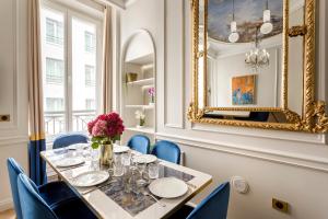 a dining room with a table with blue chairs and a mirror at Luxury 2 Bedroom 1 Bathroom - Louvre Museum & Opera in Paris
