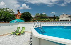 - une piscine avec 2 chaises et un parasol dans l'établissement 2 Bedroom Beautiful Home In Orihi, à Orihi