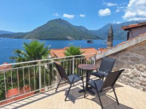 a balcony with two chairs and a table and a view of the water at Forteca home in Perast