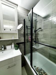 a bathroom with a shower and a sink and a tub at Acrey 