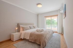 a white bedroom with a large bed with a window at Belo Horizonte Apart in Parede +28 photos