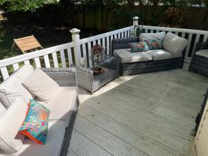 a porch with two chairs and a couch on a deck at Forest edge in Saint Leonards