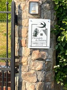 ein Schild an der Seite einer Steinmauer in der Unterkunft L’hirondelle du Faubourg 
