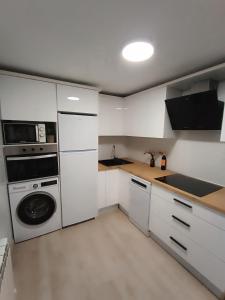 a kitchen with white cabinets and a washer and dryer at La Casita de Requejo in Zamora