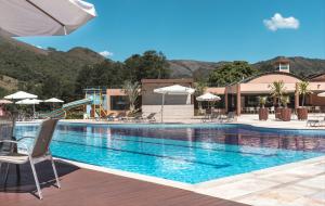 a swimming pool with chairs and a slide in a resort at Engenho da Serra Hotel EcoResort in Capitólio