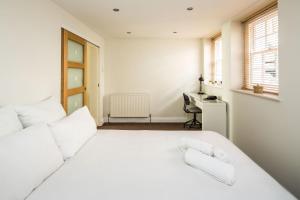 Habitación blanca con cama blanca y escritorio. en Elegant 2BD Duplex with Outdoor Patio/Glass Canopy, en Londres