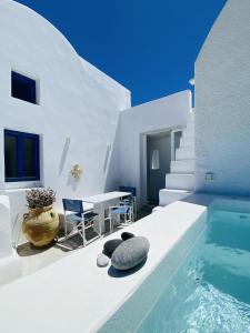 Sunset Pyrgos في بيرغوس: بيت ابيض فيه مسبح وطاولة وكراسي