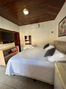 a bedroom with a large white bed and a tv at Pousada Vila Velha in Pirenópolis +84 photos