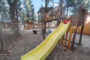 a playground with a yellow slide in a yard at Irie's Retreat - Perfect location for multi-generational groups! Sauna, hot tub, Jungle gym! in Sugarloaf