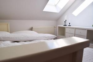 a white bedroom with two beds and a skylight at Wattwürmchen in Wremen
