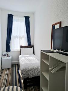 a bedroom with a bed and a desk with a television at Beverley Dean - Children Over 5 Years Welcome - Continental Breakfast in Blackpool