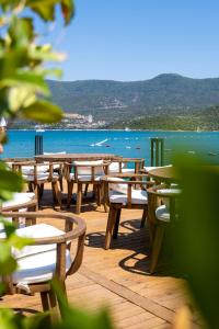 a row of tables and chairs on a deck near the water at Torbahan Hotel in Torba