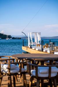 a wooden pier with tables and chairs on the water at Torbahan Hotel in Torba