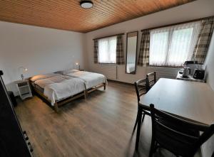 Schlafzimmer mit einem Bett, einem Tisch und Fenstern in der Unterkunft Bonne Auberge Les Bugnenets in Le Paquier
