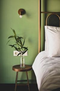 Paliani Hotel في ميستيا: زرع في مزهرية على طاولة بجانب سرير