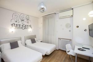 a bedroom with two beds and a desk and a table at Casual de la Música Valencia in Valencia