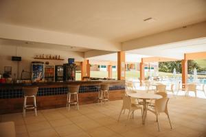 a restaurant with tables and chairs and a bar at Engenho da Serra Hotel EcoResort in Capitólio