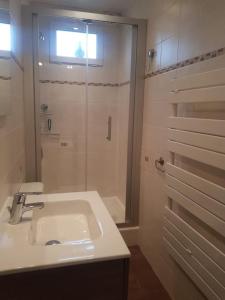 a white bathroom with a sink and a shower at Maison Bateau in Lion-sur-Mer
