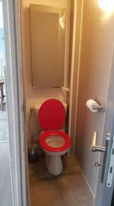 uma casa de banho com um WC vermelho com um assento vermelho em Maison Bateau em Lion-sur-Mer