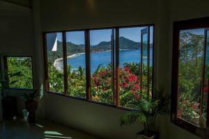 a room with four windows with a view of a beach at Monkey Flower Villas in Koh Tao