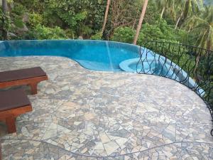 a patio with a pool and a table and bench at Monkey Flower Villas in Koh Tao