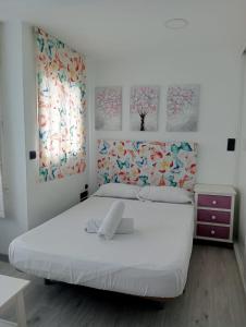 TORREMOLINOS CENTER ESTUDIO Sun & Beach في توريمولينوس: غرفة نوم بسرير ابيض ولوحتين على الحائط