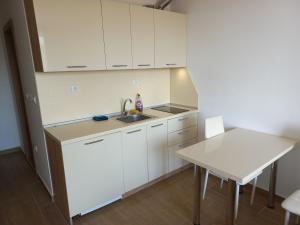 una cucina con mobili bianchi, un lavandino e un tavolo di Cascadas Family Resort a Sunny Beach
