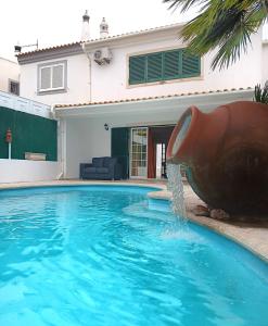 a pool with a water fountain in front of a house at Alma Rustica in Albufeira